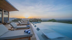 Evigheds-pool med liggestole og havudsigt i solnedgang.