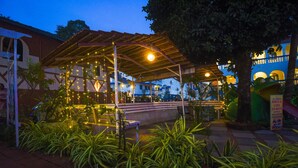 Ein Sitzbereich im Freien mit Lichterketten, einem überdachten Pavillon und Kübelpflanzen.