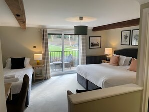 A hotel room with a bed, a chair, a desk, a lamp, and a view of the outdoors. - Cottesmore Hotel Golf & Country Club (Crawley)