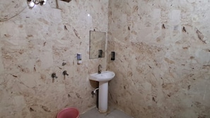 Ein Badezimmer mit einem weißen Waschbecken, einem Spiegel und einem roten Eimer auf dem Boden.