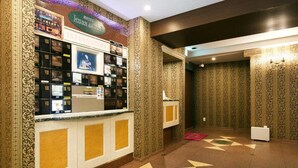 A reception area with a counter displaying informational brochures, a patterned wall, and a geometric floor design. - Hotel Luna Modern Sakuranomiya (Osaka)