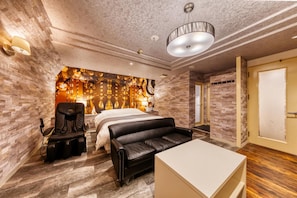 Ein modernes Hotelzimmer mit einem Bett, Massagesessel und einer Sitzecke.