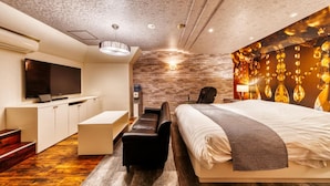 A modern hotel room with a large bed, a desk, a flat-screen TV, and a stone accent wall. - Hotel Luna Modern Sakuranomiya (Osaka)
