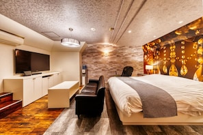 Ein modernes Hotelzimmer mit einem großen Bett, einem Schreibtisch, einem Flachbildfernseher und einer Wand mit Steinakzenten.