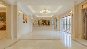 A spacious lobby with a polished marble floor, a central chandelier, and artwork on the walls. - Vienna International Hotel (Foshan)