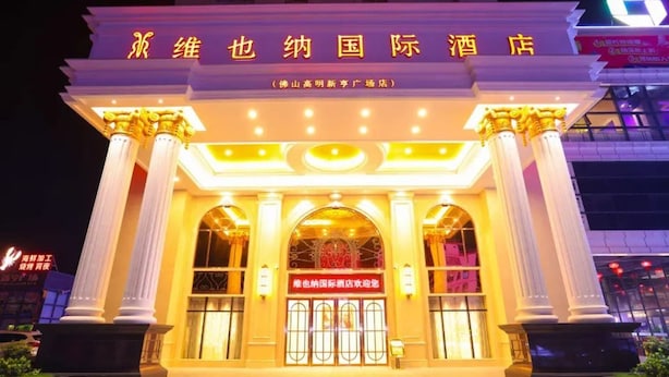 A hotel entrance with classical columns, a large arched doorway, and illuminated signage. - Vienna International Hotel (Foshan)
