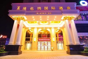 A hotel entrance with classical columns, a large arched doorway, and illuminated signage. - Vienna International Hotel (Foshan)