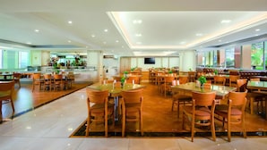 Een ruim restaurant met verschillende eetgedeeltes, een bar en een televisiescherm.