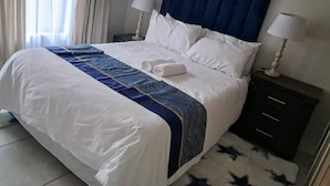 Une chambre d’hôtel avec un lit, deux lampes de chevet, une table de chevet et une fenêtre avec des rideaux.