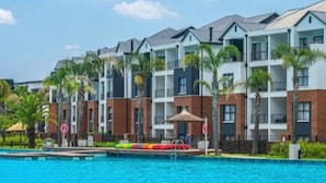 Un hôtel à plusieurs étages, doté d’une piscine et bordé de palmiers.