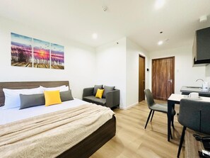 A hotel room with a bed, a sofa, a dining table, and a kitchen area. - Mangrove Place and Residences by Hiverooms (Lapu-Lapu)
