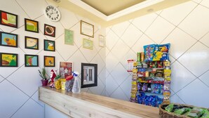 A reception area with a wooden counter, framed artwork, a clock, certificates, and a snack display. - Pousada Horizonte (Horizonte)