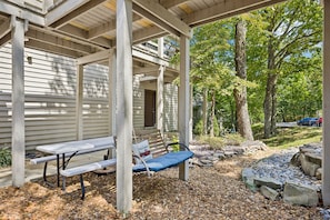 A covered outdoor area with a picnic table and bench, surrounded by trees and a stone pathway. - Villa Diane | Mountain view close to Ozone Falls! (Crab Orchard)