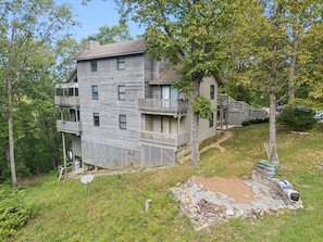 A multi-story house with a balcony, a stone fire pit, and a satellite dish.