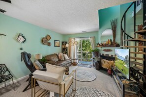 Una sala de estar con sofá, sillón, televisor y chimenea.