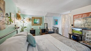 Une chambre à coucher comprenant un lit, un bureau, une chaise, un téléviseur et divers éléments de décoration murale.