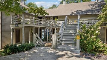 A building with a covered outdoor area, a staircase, and a caution sign for slippery surfaces.