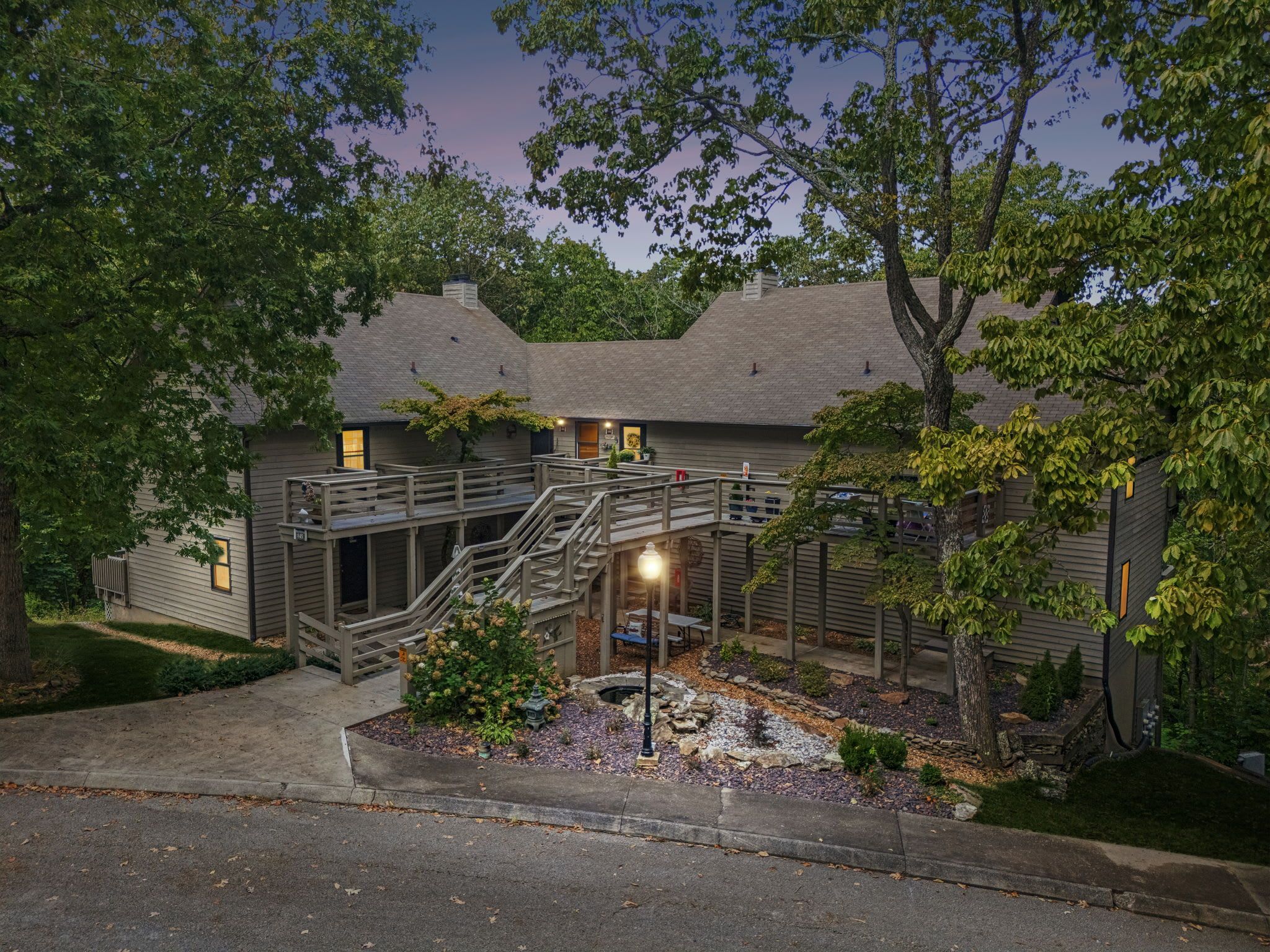 A two-story building with a covered outdoor area, a staircase, and a small garden.