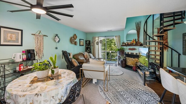 Un salon avec un ventilateur de plafond, un canapé, une table basse et un escalier.