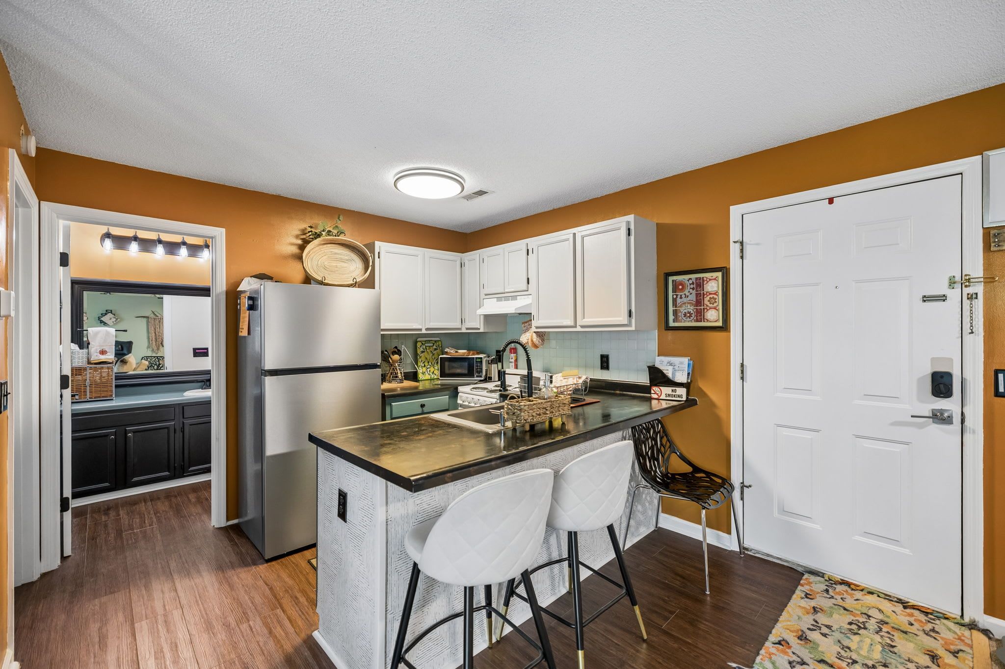 A compact kitchen with a central island, white cabinets, and a microwave.