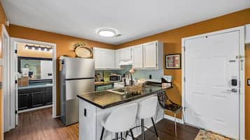A compact kitchen with a central island, white cabinets, and a microwave.