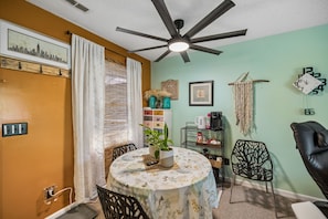 A dining area with a round table, chairs, a ceiling fan, and a wall clock. - Villa Diane | Mountain view close to Ozone Falls! (Crab Orchard)