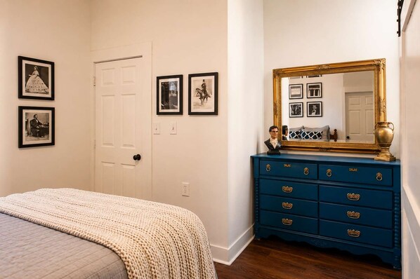 A bedroom with a bed, dresser, and wall-mounted pictures.