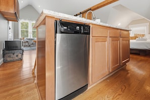 A modern kitchen with a stainless steel refrigerator, wooden cabinets, and a granite countertop. - Cozy Phoenix Hill suite in the heart of Louisville (Louisville)