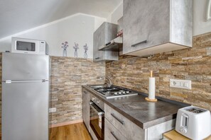 A kitchen with a stone backsplash, stainless steel appliances, and a built-in gas stove. - A spacious apartment of approximately 100 sqm, accommodating up to 7 people and laid out over two floors (with internal stairs leading to the upper level).The property is located in Tordandrea, a quiet hamlet of Assisi, in an area with good local ameniti (Tordandrea)