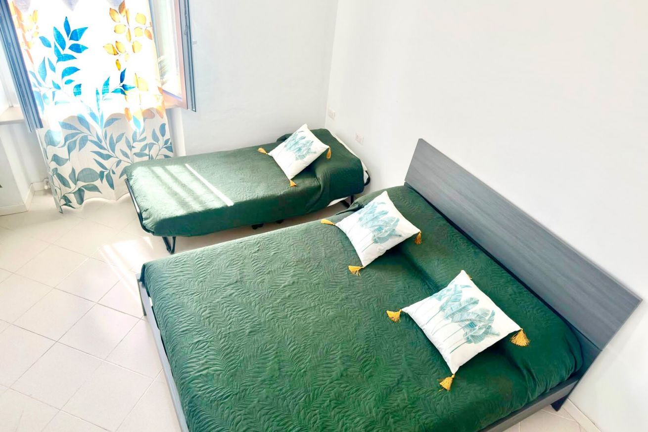 Una habitación con dos camas individuales, cada una con colcha y almohadas verdes a juego.