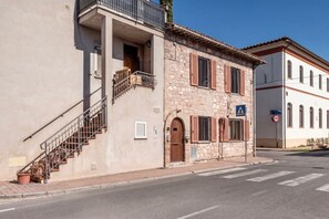 A two-story building with a staircase, a balcony, and a pedestrian crossing sign. - A spacious apartment of approximately 100 sqm, accommodating up to 7 people and laid out over two floors (with internal stairs leading to the upper level).The property is located in Tordandrea, a quiet hamlet of Assisi, in an area with good local ameniti (Tordandrea)
