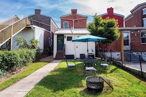 A backyard with a patio table, chairs, and a fire pit.