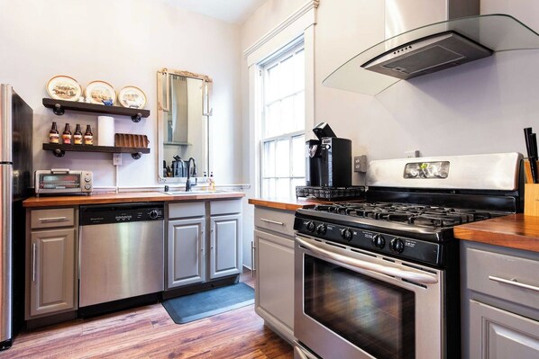 A modern kitchen with stainless steel appliances, wooden countertops, and a large window.