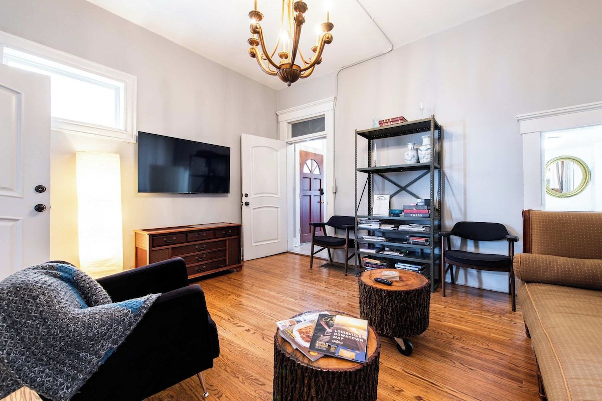 Una sala de estar con televisor de pantalla plana, candelabro, estantería y sofá.