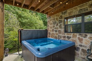 Un bain à remous avec un mur en pierre en arrière-plan et un plafond en bois.