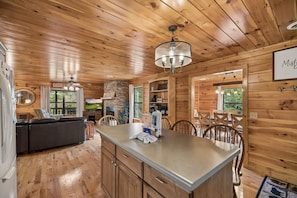 L’intérieur d’un chalet en bois comprend une cuisine, un coin repas et un salon avec une cheminée.