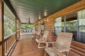 A wooden deck with a ceiling fan, a bench, and Adirondack chairs. - Smoky Mtn Cabin | Hot Tub, Fishing Pond & Views! (Sevierville)