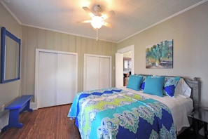 A bedroom with a bed, a ceiling fan, a painting, and a bench. - Vibrant Crescent Hill Apt close to Cherokee Park! (Louisville)