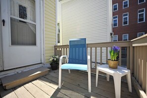 A wooden deck with a white door, a blue chair, and a small table with a potted plant. - Vibrant Crescent Hill Apt close to Cherokee Park! (Louisville)