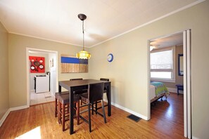 A dining area with a wooden table and chairs, a hanging light fixture, and a clock on the wall. - Vibrant Crescent Hill Apt close to Cherokee Park! (Louisville)
