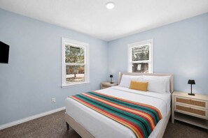 Une chambre à coucher avec un lit, deux tables de chevet, une fenêtre et une porte.