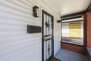Une porte d’entrée avec une boîte aux lettres, un luminaire suspendu et une fenêtre donnant sur l’extérieur.
