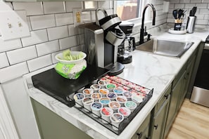 Une cuisine équipée d’une machine à café, d’un évier et d’un présentoir pour les pots de yaourt.