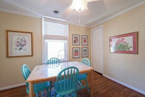 A dining area with a wooden table and turquoise chairs, a ceiling fan, and framed artwork on the walls. - Spacious 3BR Crescent Hill Apt | Yard & Parking (Louisville)