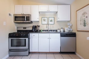 A compact kitchen with white cabinets, a microwave, a stove, and a dishwasher. - Spacious 3BR Crescent Hill Apt | Yard & Parking (Louisville)