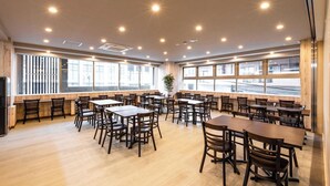 A spacious dining area with multiple tables and chairs, large windows with a view of the outside, and a modern ceiling design with recessed lighting. - Hotel Legit Hiroshima (Hiroshima)