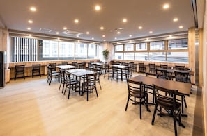 A spacious dining area with multiple tables and chairs, large windows with a view of the outside, and a modern ceiling design with recessed lighting. - Hotel Legit Hiroshima (Hiroshima)