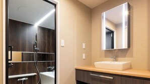 A modern bathroom with a glass shower enclosure, a white sink, and a wooden vanity. - Hotel Legit Hiroshima (Hiroshima)