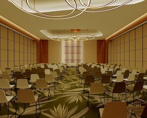 Un salón de conferencias con filas de sillas, una alfombra estampada y un moderno aplique de techo.