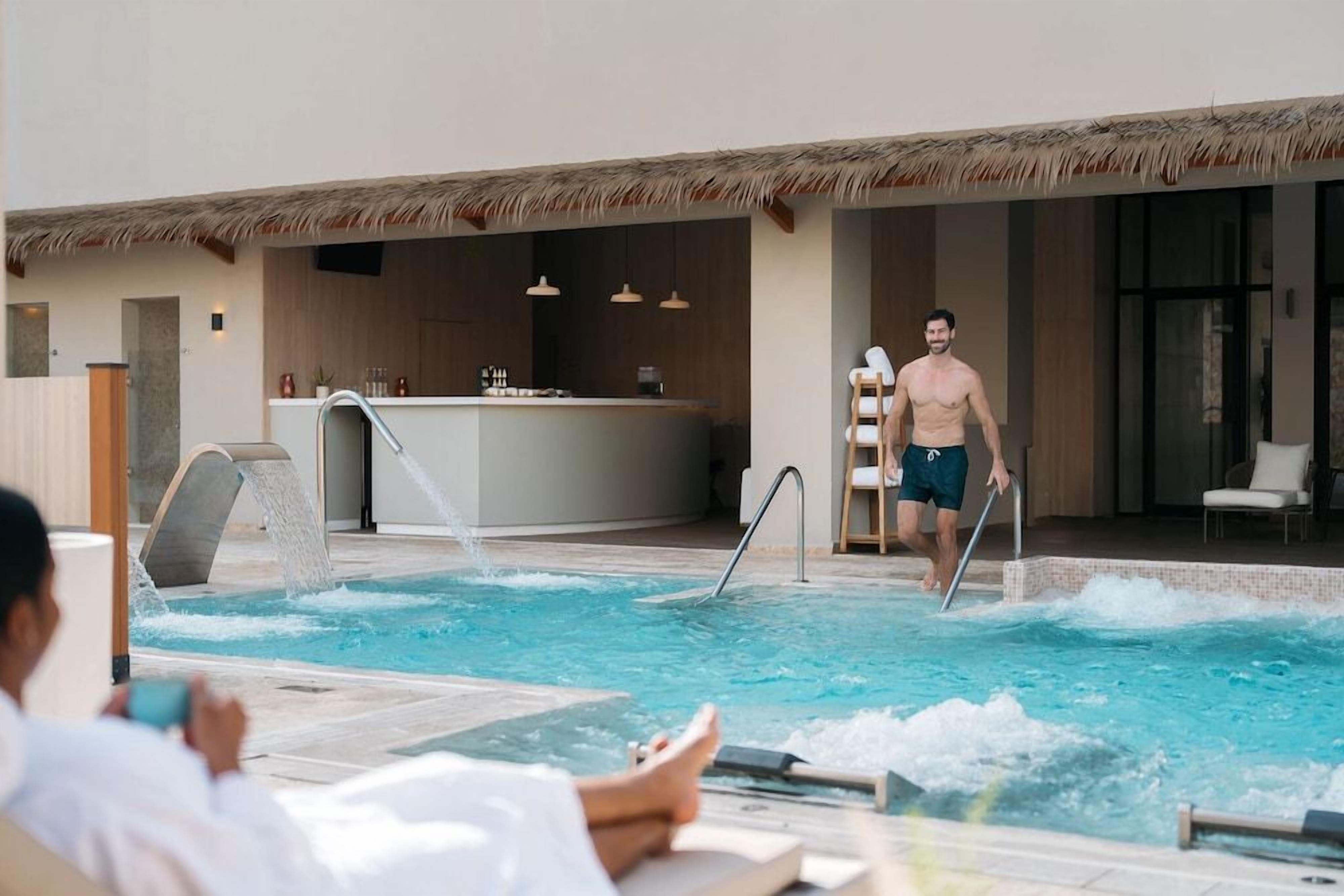 Zona de piscina con bar y sillones de descanso.